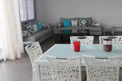 a table and chairs in a living room with a couch at Eden Island Villa - Bouznika in Bouznika