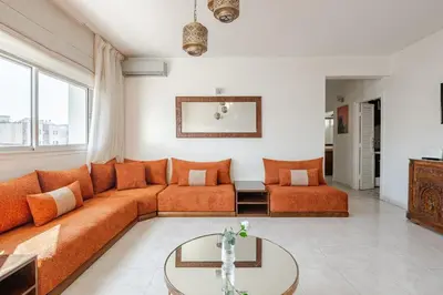 a living room with an orange couch and a table at Spacious 2Bedrooms Fully equipped-5min Agdal Station in Rabat