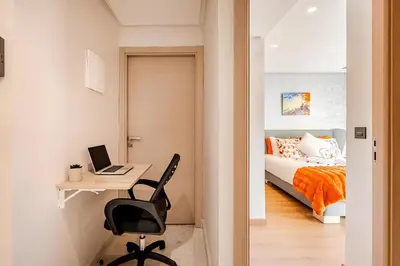 a bedroom with a bed and a desk with a laptop at Studio Cosy, corniche à 2 min , Parking , Netflix in Casablanca
