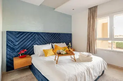 a bedroom with a large bed with a blue headboard at Appartement de Luxe - Piscine et Accès à la Plage in Bouznika