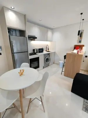 a kitchen with a white table and white chairs at Residence La Reine II 24H Reception Cosy & Central Apartment 1 Minute Near To MOHAMMED V SPORTS COMPLEX 5 Min By Car To Ain Diab Corniche With Optical Fiber Wifi Casablanca in Casablanca