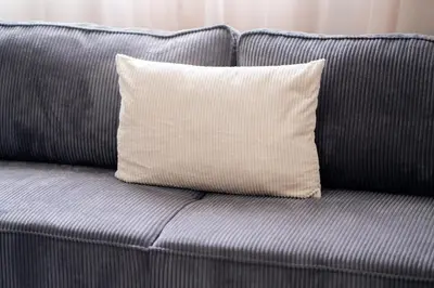 a gray couch with a white pillow on it at Appartement Premium avec Piscine in Mohammedia