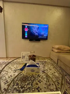 a living room with a coffee table with a tv on the wall at Studio proche clinique akdital ain sebaa in Casablanca