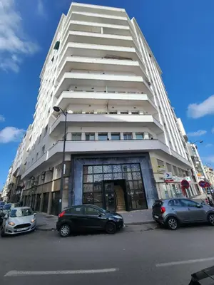 a tall white building with cars parked in front of it at The 31 Grand Théâtre by IB Signature - Boho Chic 1BR Apt - with Wifi - Self check-in - 24 x7 Security - City View with terrace - Walk to Cafes! City Centre, Tram in Casablanca