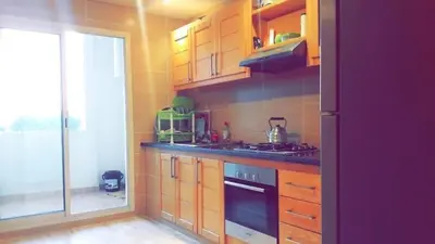 a kitchen with wooden cabinets and a stove top oven at Appartement de luxe à 3 min de l aéroport in Nouaseur