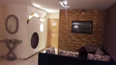 a living room with a couch and a tv on a brick wall at Appartement de luxe à 3 min de l aéroport in Nouaseur