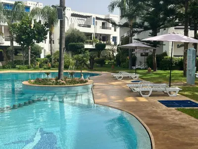 a swimming pool with chairs and umbrellas next to a building at Évasion océanique skhirat in Skhirat