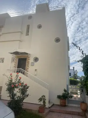 a white house with a staircase and plants on it at Maison fantastique à louer à Harhoura près de la plage Votre maison côtière de rêve in Temara
