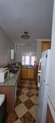 a kitchen with a white refrigerator and a tile floor at Blue Wave Apartment in Temara