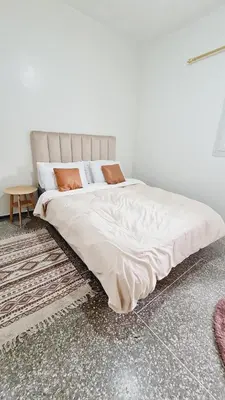 a bedroom with a large bed with white sheets and orange pillows at 3Bed-Room Appart Agdal City Center in Rabat
