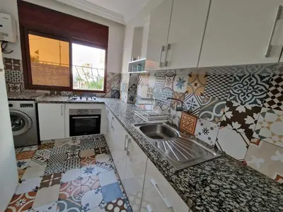 a kitchen with a sink and tiles on the wall at Elégant 3 pieces salon pour famille à 3 min de Hay riad Rabat in Temara