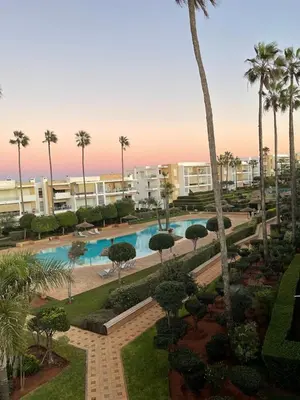 a view of a pool with palm trees and buildings at Beachside Charming Apartment in Tamaris