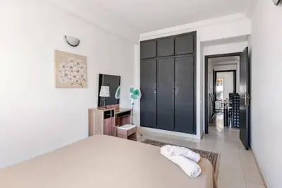 a bedroom with a white bed and a black cabinet at Appartement Agdal, proche des stades in Rabat