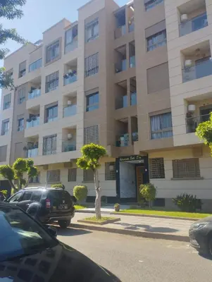 a large building with cars parked in front of it at The Park Apartment in Mohammedia