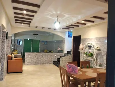 a dining room with a table and a living room at RiadNA bouznika in Bouznika