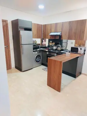 a kitchen with a refrigerator and a table in it at Séjour serein près aéroport in Nouaceur
