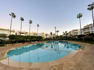 a large swimming pool in a resort with palm trees at Beachside Charming Apartment in Tamaris