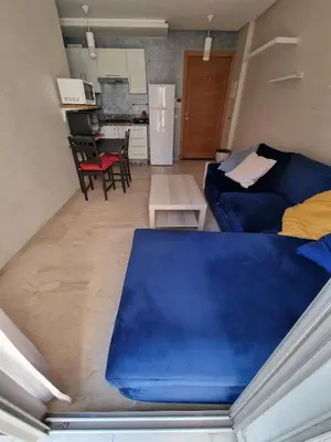 a living room with a blue couch and a kitchen at Heart of Casablanca - Tramway in Casablanca