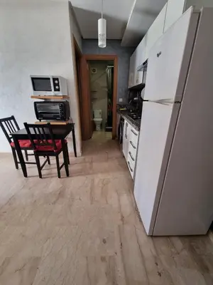 a kitchen with a refrigerator and a table with a chair at Heart of Casablanca - Tramway in Casablanca