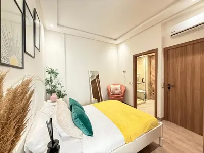a bedroom with a bed and a chair in it at Cosy Patio sunny 2BR - new building - near oasis train station in Casablanca