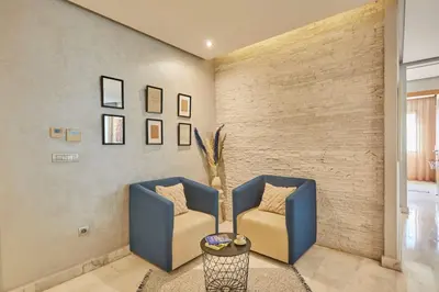 a living room with two blue chairs and a brick wall at Luxury 3 Bedroom Getaway in Bouskouras Finest in Bouskoura