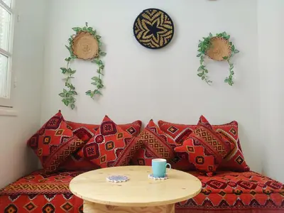 a couch with red pillows and a wooden table at Suite DeLuxe au coeur de la ville in Casablanca