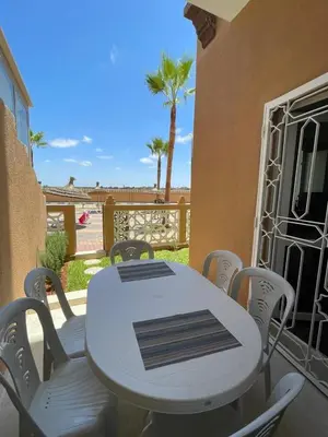 a white table and chairs on a balcony with palm trees at Al Kawtar in Mansouria