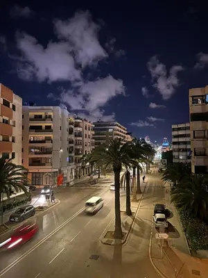 a city street at night with cars and palm trees at Luxurious studio with view gym parking and keyless access in Casablanca