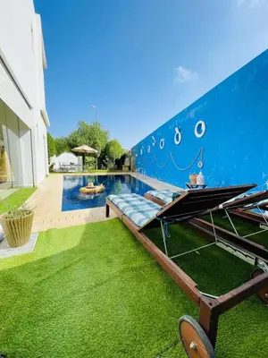 a pool with green grass next to a building at Villa with rooftop bar overlooking sea, pool & vegetable garden in Tamaris