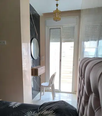 a bedroom with a bed and a chair and a mirror at apartment a casablanca in Dar Ben Abdallah Ben Dehbi