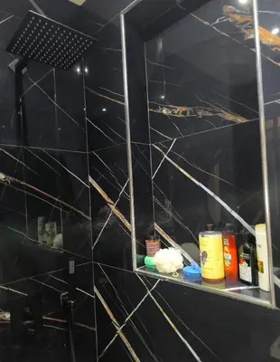 a bathroom with black tiled walls and a shelf at apartment a casablanca in Dar Ben Abdallah Ben Dehbi