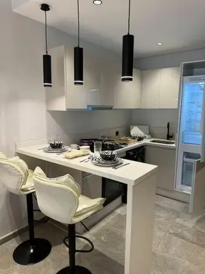 a kitchen with a white counter and chairs in it at Studio Chic Princesses Maarif - Wifi haut débit in Casablanca