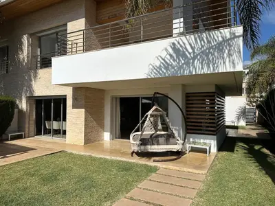 a house with a swing on the side of it at Bouznika Bay Villa Prestigious Oasis in Sidi el Haj Bou Derbala