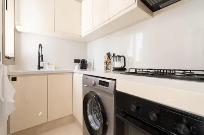 a white kitchen with a washing machine in it at Modern & bright studio Balcony & Parking Maarif in Casablanca