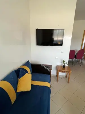 a living room with a blue couch and a flat screen tv at Mansoria in Mansouria