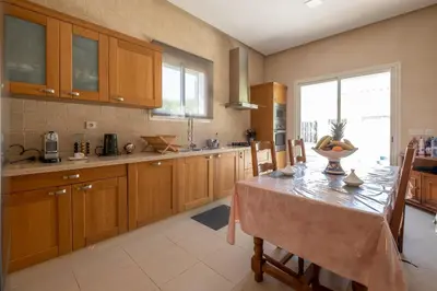 a kitchen with wooden cabinets and a table with chairs at Superb Villa in Bouznika with Private Pool & Hammam in Bouznika