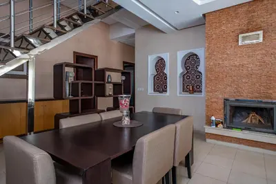 a dining room with a table and chairs and a fireplace at Superb Villa in Bouznika with Private Pool & Hammam in Bouznika