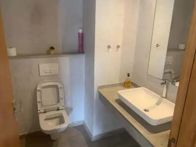 a bathroom with a white toilet and a sink at Appartement avec une Chambre, Salon, Salle de Bain et Piscine in El Harhoura