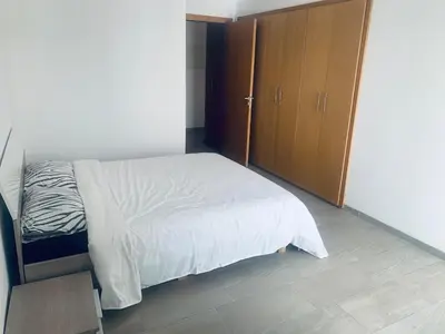 a bedroom with a bed and a wooden cabinet at Appartement avec une Chambre, Salon, Salle de Bain et Piscine in El Harhoura