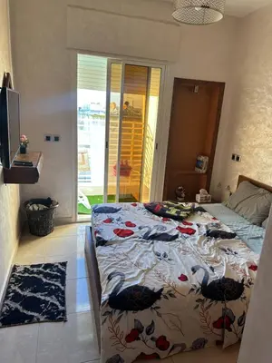 a bedroom with a bed with a floral comforter at appart 206 in Temara