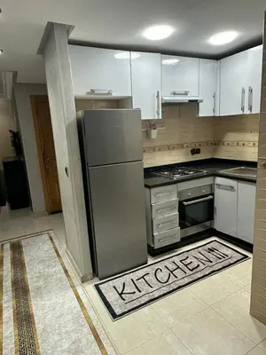a kitchen with a stainless steel refrigerator and white cabinets at appart 206 in Temara