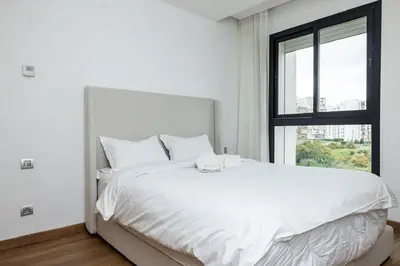 a white bed in a room with a window at Luxurious and comfortable in Prestigia in Rabat