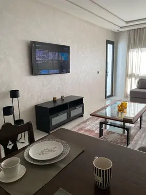 a living room with a table and a tv on the wall at Appartement in Casablanca