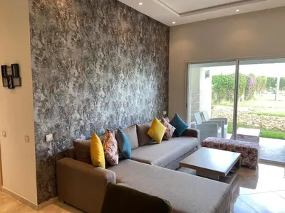 a living room with a couch and a wall at CASABAY Sidi Rahal, appartement avec accès direct à la piscine in Sidi Rahal