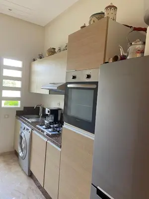 a kitchen with a refrigerator and a washing machine at CASABAY Sidi Rahal, appartement avec accès direct à la piscine in Sidi Rahal