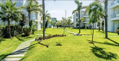 a park with palm trees in front of buildings at CASABAY Sidi Rahal, appartement avec accès direct à la piscine in Sidi Rahal