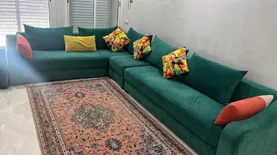 a green couch with pillows on it in a living room at Les Jardins de Bouznika Premium - Votre espace familial in Bouznika