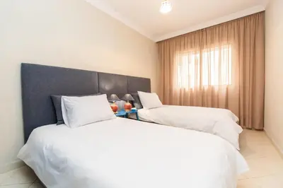 two beds in a hotel room with white sheets at Cozy apartment 5 minutes from Casa Voyageurs in Casablanca