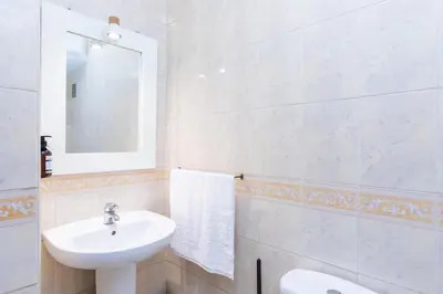 a white bathroom with a sink and a mirror at Cozy apartment 5 minutes from Casa Voyageurs in Casablanca