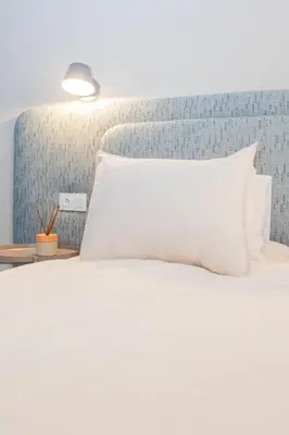 a bed with a white pillow on top of it at Cozy apartment 5 minutes from Casa Voyageurs in Casablanca